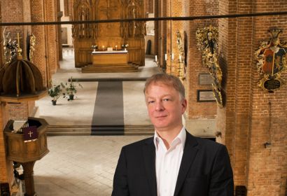 Prof. Dr. Guntars Prānis in der Petrikirche in Riga. Foto: Prānis/Förderverein Orgel der Petri-Kirche Riga, Montage: Martin Pabst