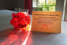 Rote Plastikschweinchen werben rund um den Welthospiztag um Spenden.