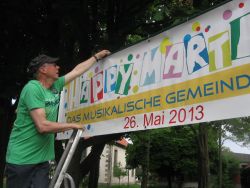 Die Vorbereitungen laufen auf Hochtouren für Happy Martini: Horst Sauk hängt in Engelbostel ein Transparent auf fürs Gemeindefest.