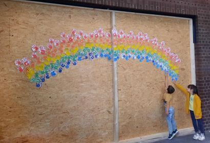 Ein Regenbogen aus bunten Kinderhänden bringt Farbe auf die provisorische Trennwand. Foto: Sebastian Müller