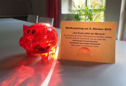 Rote Plastikschweinchen werben rund um den Welthospiztag um Spenden.