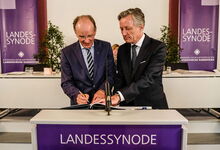 Die erste Unterschrift unter dem ersten gebundenen Exemplar der neuen landeskirchlichen Verfassung leistete Landesbischof Ralf Meister (links); Synodenpräsident Dr. Matthias Kannengießer folgte. Foto: Jens Schulze
