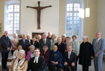 Die Jubilarinnen und Jubilare der Konfirmationsjahrgänge 1948, 1953 und 1958 mit Pastor Thorsten Buck (vorne rechts) vor dem Altar von St. Michaelis. Foto: Henrike Hein