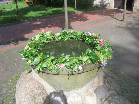 Zu Pfingsten wird der Alte Taufstein vor der Martinskirche für 16 Täuflinge mit Blumen geschmückt.