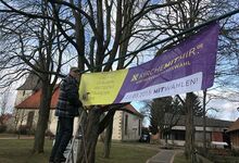 Horst Sauk wirbt für die Kirchenvorstandswahl und hängt ein Transparent vor der Martinskirche auf.