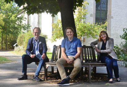 „Er passt einfach zu uns“: Merlin Langrehr (Mitte) mit Pastor Rainer Müller-Jödicke und Kirchenvorsteherin Jutta Köster vor der Martinskirche. Foto: Andrea Hesse