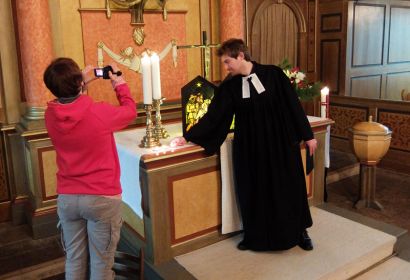 Stephanie Hamburg filmt Vikar Hendrik Hundertmark am Altar der Martinskirchengemeinde. Foto: Rainer Müller-Jödicke