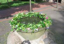 Zu Pfingsten wird der Alte Taufstein vor der Martinskirche für 16 Täuflinge mit Blumen geschmückt.