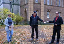 Kreisarchivpfleger Dr. Frank Foerster (rechts) und Pastorin Debora Becker überreichen Ralf Backhaus eine Kopie des alten Kaufvertrages. Foto: Andrea Hesse