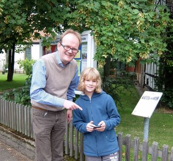Ben Koch (11) erklärt Pastor Rainer Müller-Jödicke am Engelbosteler Pfarrhausschild die Pokémon GO-Spielregeln.