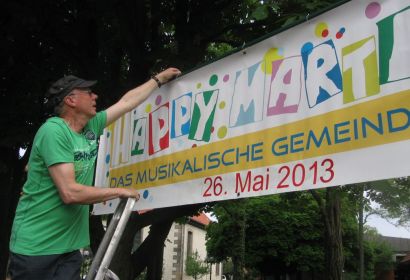 Die Vorbereitungen laufen auf Hochtouren für Happy Martini: Horst Sauk hängt in Engelbostel ein Transparent auf fürs Gemeindefest.