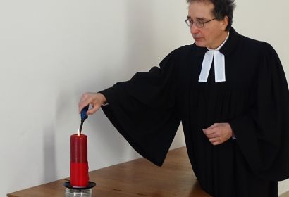 In der Pauluskirche in Langenhagen zündet Pastor Frank Foerster eine Kerze zum Gedenken an die Opfer der Covid-19-Pandemie an. Foto: GunterM