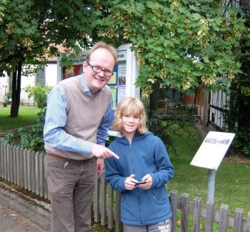 Ben Koch (11) erklärt Pastor Rainer Müller-Jödicke am Engelbosteler Pfarrhausschild die Pokémon GO-Spielregeln.