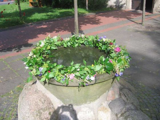 Zu Pfingsten wird der Alte Taufstein vor der Martinskirche für 16 Täuflinge mit Blumen geschmückt.