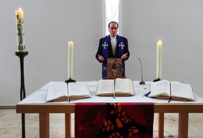 Pastor Frank Foerster betet am Altar der St.-Paulus-Kirche und lädt dazu ein, zeitgleich mit ihm zu Hause zu beten.