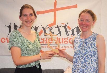 Wie einen Staffelstab übergibt Mary Pattke (rechts) das Symbol der Evangelischen Jugend, das Kreuz auf der Weltkugel, an Rebecca Wülbern. Foto: Andrea Hesse