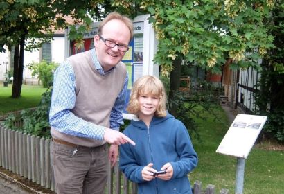 Ben Koch (11) erklärt Pastor Rainer Müller-Jödicke am Engelbosteler Pfarrhausschild die Pokémon GO-Spielregeln.